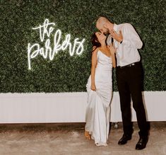 a bride and groom kissing in front of a wall with the words mr and mrs written on it