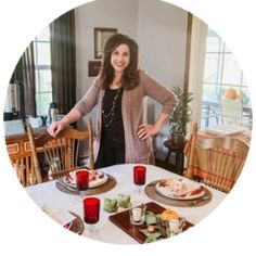 a woman standing in front of a table with food on it and candles around her