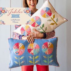 a woman holding two decorative pillows with flowers on them and a sign that says jubilee