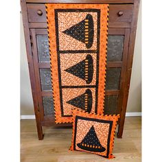 two quilted pillows sitting on top of a wooden cabinet