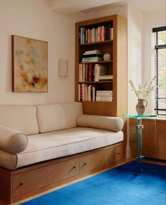 a living room with a couch, book shelf and glass table in front of it