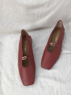 a pair of red shoes sitting on top of a white sheet