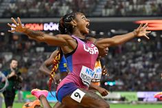 a woman in a pink and blue shirt is running with her arms spread wide out