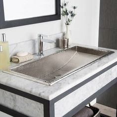 a bathroom sink sitting under a mirror next to a towel rack and soap dispenser