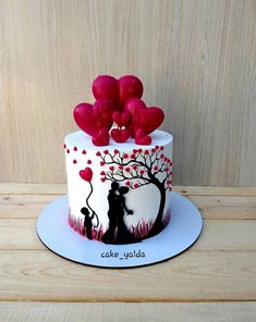 a cake decorated with red balloons and a silhouette of a couple holding each other's hands