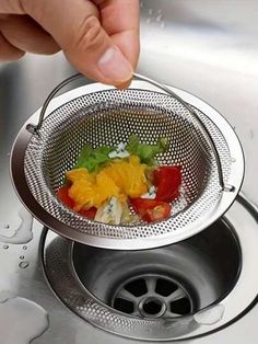 a strainer filled with vegetables sitting on top of a sink