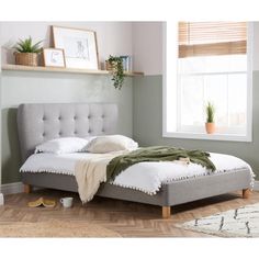 a bed sitting in a bedroom on top of a hard wood floor next to a window