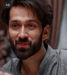 a close up of a person with a beard and wearing a gray shirt looking at the camera