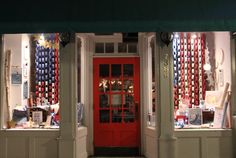 a store front with red door and many items on display in it's windows