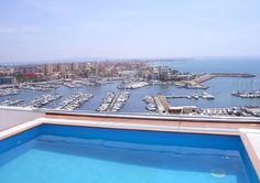 an outdoor swimming pool overlooking a marina with boats in the water and buildings on the other side