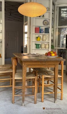 a wooden table and chairs in a room with bookshelves behind it, next to an open door