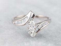 The polished lines on this marquise cut diamond engagement ring is a thing of spectacular beauty! The sleek curves of the center gem echo in the elegant design of the bypass style mounting, which is encrusted in sparkling baguette-cut diamonds. Metal: 14K White Gold Gem: Diamond .16 Carats, VVS in Clarity, E in Color Gem Measurements: 3.0 x 5.3 mm, Marquise Cut Accents: 20 Diamonds totaling .50 Carats, VVS in Clarity, G in Color Ring Size: 7.75 Marks: "14K..." Stamped on the inside band Marquise Bypass Engagement Ring, Marquise Cut Diamond Engagement Rings, Bypass Engagement Ring, Marquise Diamond Engagement Ring, Sapphire Solitaire Ring, Marquise Diamond Ring, Ring Marquise, Bypass Ring, Marquise Cut Diamond