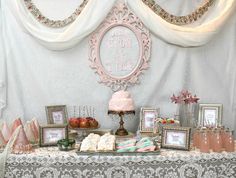 a table topped with pictures and cakes under a white drape covered wall next to framed photos