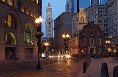 an empty city street at night with lights on and buildings in the backround