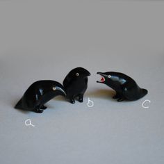 three small black birds with mouths open on a table