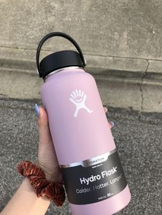 a hand holding a pink hydro flask water bottle