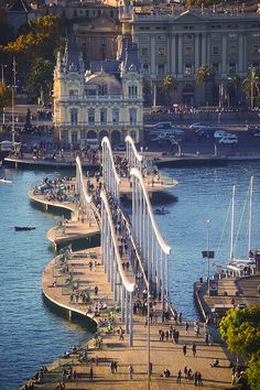 people are walking on the bridge over the water