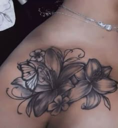 the back of a woman's stomach with flowers on it and butterflies flying around