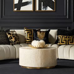 a living room with black walls and white couches, gold accents on the coffee table