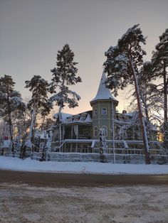 a large green house surrounded by trees covered in snow