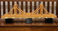 a model of the golden gate bridge is shown in front of a wooden bench with lights on it