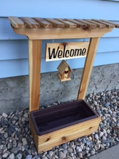 a wooden welcome sign with a birdhouse on it