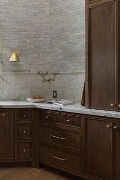 a kitchen with wooden cabinets and marble counter tops, along with a gold light hanging from the ceiling