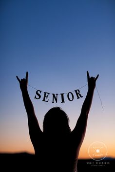 the silhouette of a woman with her hands up in the air holding a sign that says senior