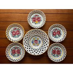 six plates with floral designs on them sitting on a wooden table