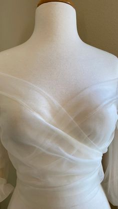 a white dress on a mannequin with ruffles around the bust and shoulders