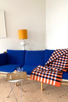 a blue couch sitting on top of a hard wood floor next to a white wall