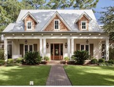 a house with white trim and brown shingles on the roof, front door and porch