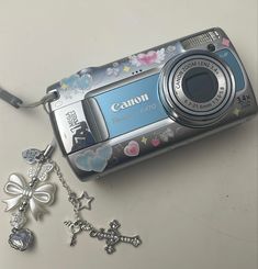 a digital camera sitting on top of a table next to a cross and keychain