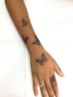 a woman's hand with butterfly tattoos on her left wrist and the other arm