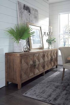 a wooden sideboard with a mirror on top of it next to a dining room table