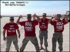 four men in red shirts and camo pants are standing together with their hands up