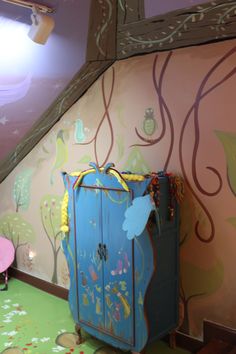 a child's room with a blue cabinet and pink chair in the corner, under a slanted ceiling