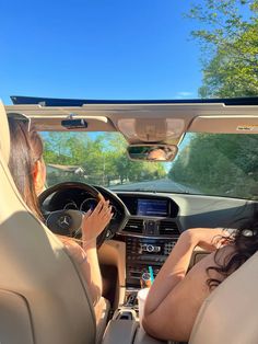 two women sitting in the driver's seat of a car