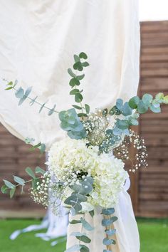 a vase filled with white flowers and greenery