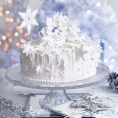 a white frosted cake sitting on top of a glass plate covered in snowflakes