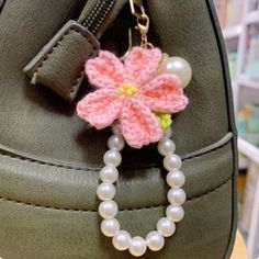 a pink flower is attached to a green purse