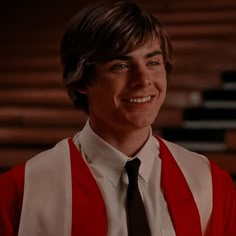 a young man wearing a red vest and tie