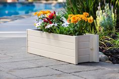 a wooden planter filled with flowers next to a swimming pool