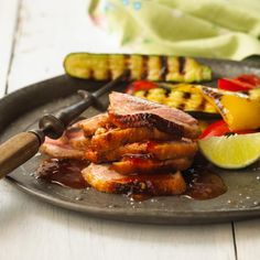 a plate with meat and vegetables on it next to a grilling spatulas