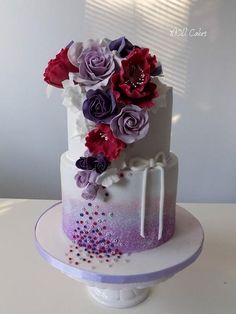 a white cake with purple and red flowers on it