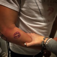 two people holding each other's hands with lipstick painted on the arm and hand