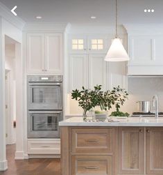 a kitchen with white cabinets and an island in the middle is lit by two pendant lights