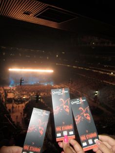 three people holding up their tickets in front of an audience at a concert or show