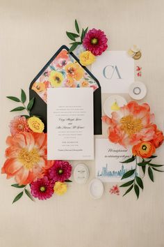 the wedding stationery is surrounded by flowers and other things to include an envelope, ring