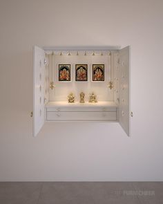 an open white shelf with two pictures on the wall and lights above it in front of them